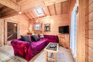 a living room with a purple couch and a tv at Chalet 6p Classique - Les Biches in Verchaix