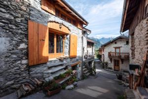 a stone house with wooden doors on a street at Chambre d'hôte Chalet le Persan in Courchevel