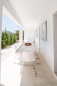 a white dining room with a long table and white chairs at Villa La Vida in Cala Llonga