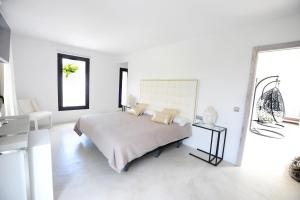 a white bedroom with a bed and a table at Villa La Vida in Cala Llonga +49 photos