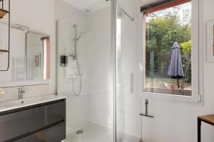 a white bathroom with a shower and a sink at A L'orée D'angers - Terra Botanica in Avrillé +8 photos