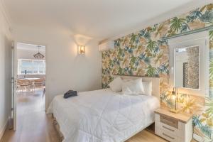a bedroom with a white bed with a tropical wallpaper at Monterojo San Agustin Las Burras in San Agustin +17 photos