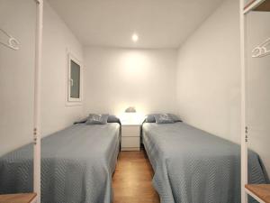 two beds in a room with white walls and wooden floors at Primera linea Sant Antoni Calonge in Sant Antoni de Calonge