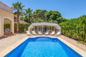 a swimming pool with chairs and a gazebo at Villa Paula in Sa Ràpita