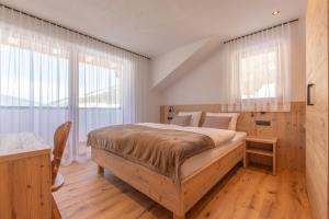 a bedroom with a large bed with wooden floors and windows at Metzgermayr in Villabassa