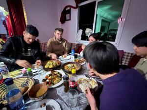 a group of people sitting around a table eating food at Merzouga Infinity Dunes Camp in Merzouga