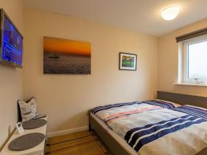 a bedroom with a bed and a tv on the wall at Fewo Op de Warft in Pellworm