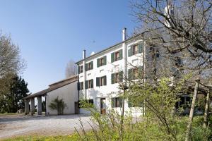a white building with a lot of windows at Agriturismo Marzanino in Torre di Mosto