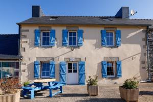 a building with blue shutters and a picnic table in front of it at Chambre Breizh in Cast