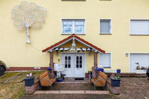 a yellow house with chairs in front of the door at App und Fewos Wolf in Usingen