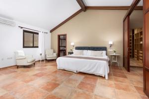 a bedroom with a large white bed and two chairs at Villa Selena in Pájara