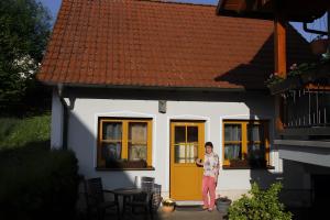 a woman standing in front of a house with a yellow door at Ferienwohnung Stark in Scheßlitz