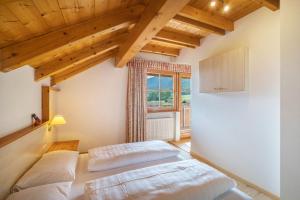 two beds in a room with a window at Oberhölzlhof in Valdaora di Sopra