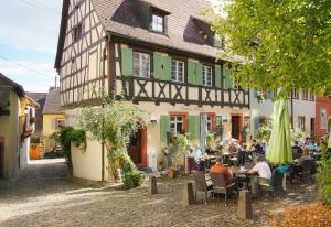 a group of people sitting at tables in front of a building at Gästehaus Siebter Himmel in Burkheim