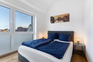 a bedroom with a bed with blue sheets and a window at White House Apartments in Kappel-Grafenhausen
