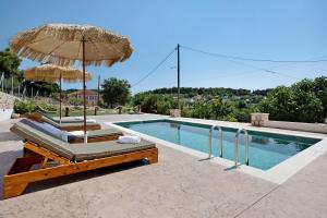 a swimming pool with two chairs and an umbrella at Christine's House in Zakynthos