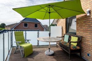 a green umbrella on a balcony with a table and chairs at Ferienwohnung 'Sonneck' in Eckernförde