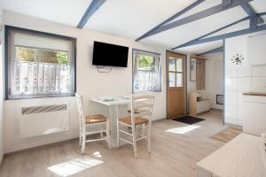 a living room with a table and chairs and a tv at Bungalow Netzboden, Bgl 28 in Dranske