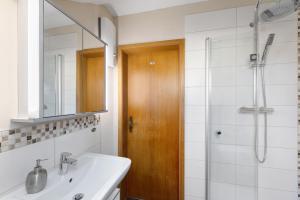 a bathroom with a sink and a shower with a mirror at Ferienwohnung Obrighoven in Wesel +20 photos