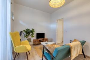 a living room with a couch and chairs and a tv at Le Voltaire pour 4 in Sète