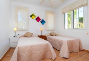 two beds in a room with white walls and windows at Verano in Calpe +31 photos