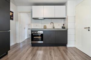 a kitchen with black and white appliances and wooden floors at Ferienwohnung zur Grenze in Gronau