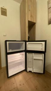 an empty refrigerator with its doors open in a room at Appartment nahe Galopprennbahn in Iffezheim +15 photos