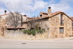 an old stone house on the side of a street at El Molino del pepe in Almajano