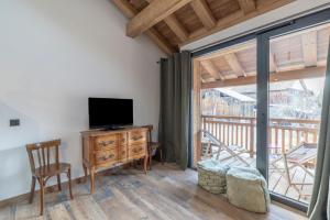 a living room with a television and a balcony at Les Petits Loups in Morillon