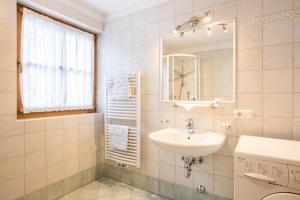 a white bathroom with a sink and a mirror at Ciasa Tlara App Alma in San Vigilio Di Marebbe