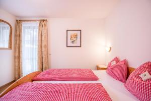 a bedroom with two red beds and a window at Ciasa Tlara App Alma in San Vigilio Di Marebbe