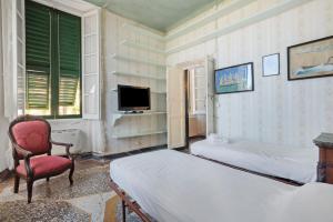 a bedroom with two beds and a chair and a tv at Piazza 100 Croci in Bonassola