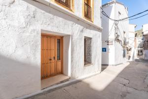 a white building with a wooden door on a street at Cueva De La Portería in Chulilla