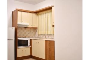 a small kitchen with white cabinets and a refrigerator at Manolika Studio 6 in Kithnos