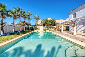 a swimming pool with palm trees and a house at Kuko Beach Denia in Denia