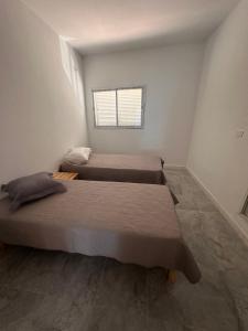 two beds in a white room with a window at Appartement melita aéroport in Mellita