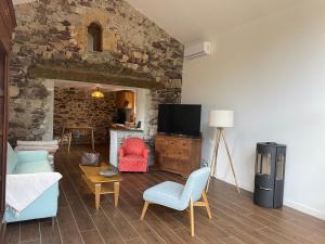 a living room with a tv and a stone wall at Maison Gaia in Valdeblore