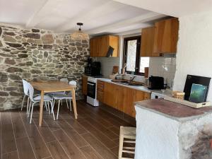 a kitchen with a table and a stone wall at Maison Gaia in Valdeblore