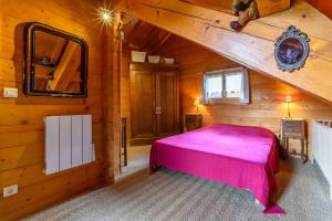 a bedroom with a pink bed in a wooden cabin at Chalet Du Wason in Xonrupt-Longemer