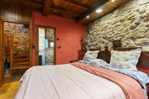 a bedroom with a large bed in a stone wall at La Casa De La Torre in Dosango