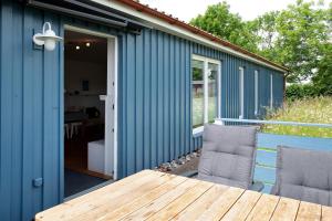 a blue house with a wooden table and chairs at Möve Aba Bungalow 68 in Rerik