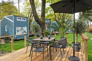 a table and chairs on a deck with an umbrella at Tiny House Nr 6 in Schwielowsee