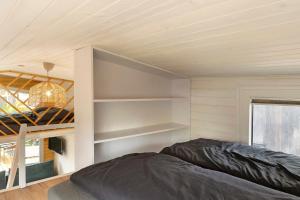 a bedroom with a bed and shelves in a room at Tiny House Nr 6 in Schwielowsee
