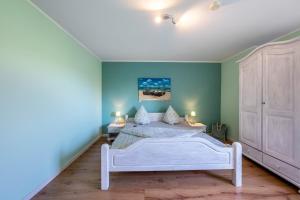 a bedroom with a white bed and blue walls at Ferienhof Dethlefsen in Pellworm