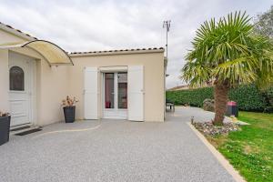 a building with a palm tree in front of it at Chambre chez l'habitant proche mer in Saujon