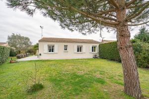 a white house with a tree in the yard at Chambre chez l'habitant proche mer in Saujon