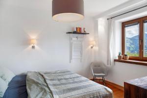 a bedroom with a bed and a chair and a window at Bergnest Penning in Hopfgarten im Brixental
