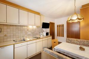a kitchen with white cabinets and a sink and a table at Untersinnerhof Gsies in Valle Di Casies +85 photos