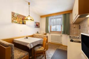 a dining room with a table and a kitchen at Untersinnerhof Gsies in Valle Di Casies