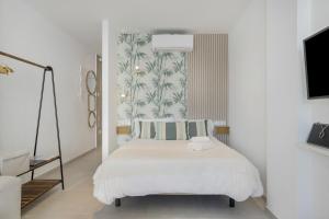 a white bedroom with a bed and a tv at Apartamento Bambú 2 10 in Tarifa +17 photos